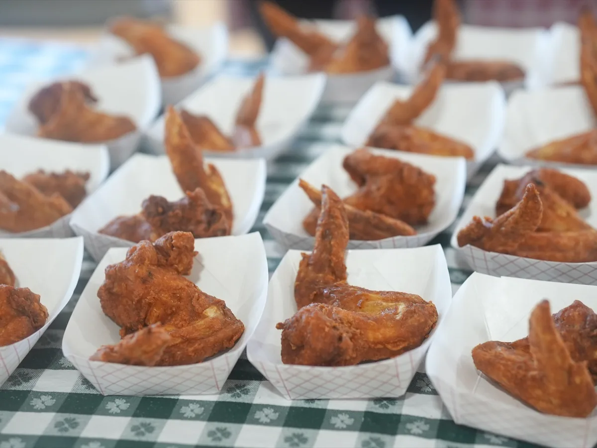 Rows of golden fried chicken wings portioned into paper trays ready to serve