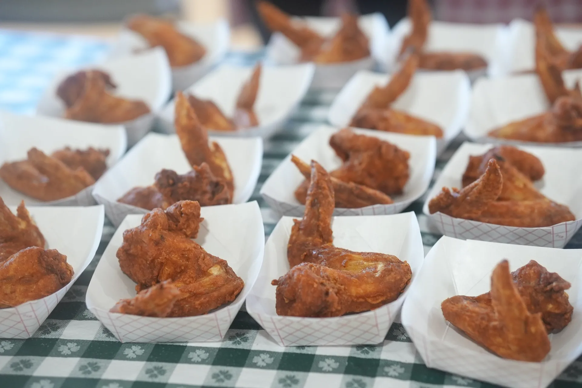 Rows of golden fried chicken wings in paper trays at a vendor booth during the Austin Chicken Wing Festival